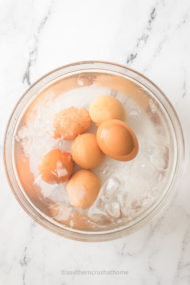 brown hard boiled eggs chilling in ice bath bowl