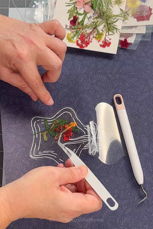 using tweezers to place dried flowers on sticker
