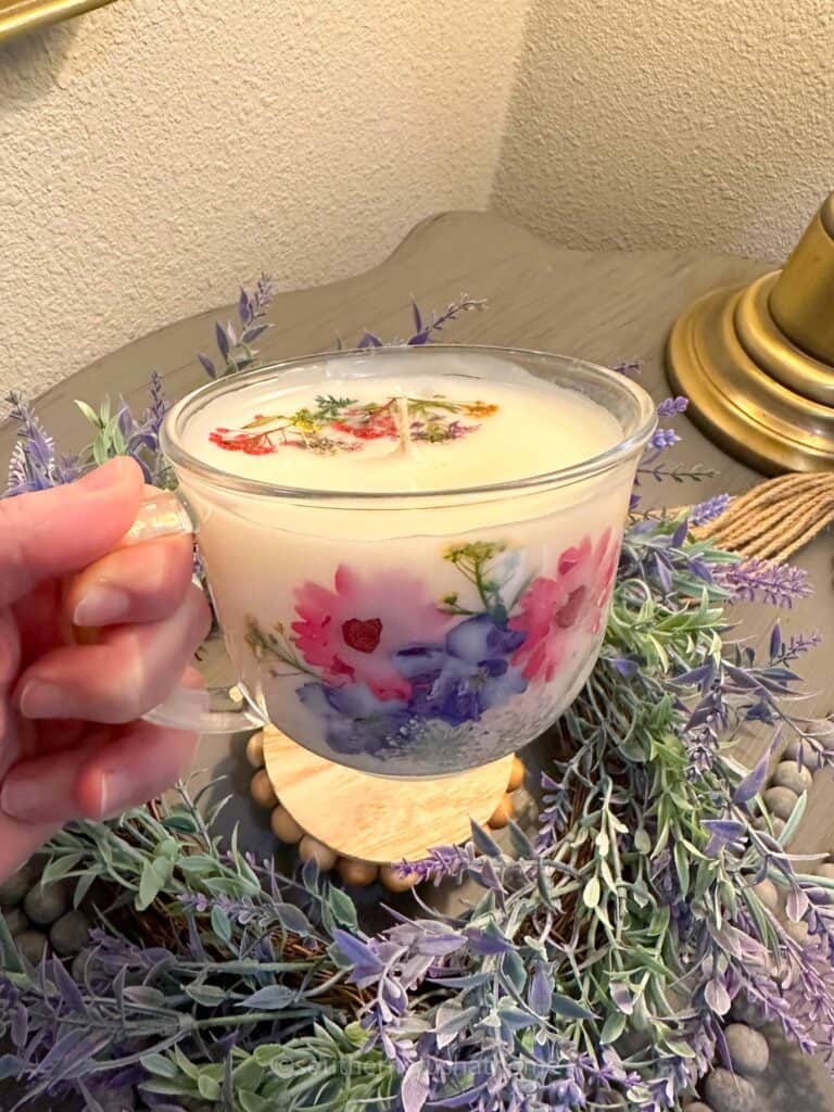 holding up a tea cup candle with dried flowers
