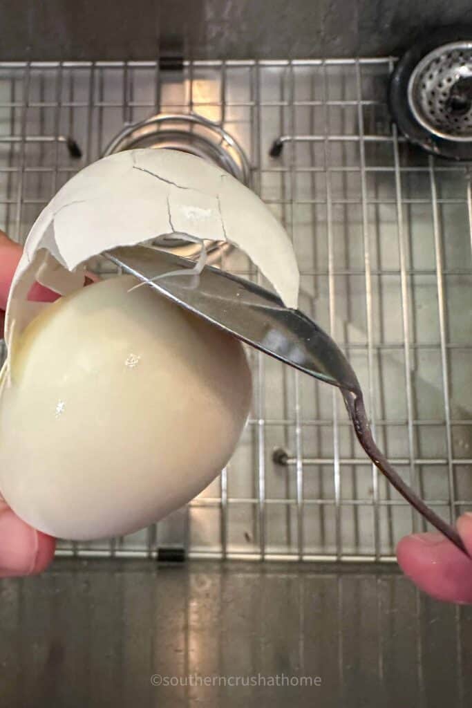 removing egg shell from boiled egg with a spoon