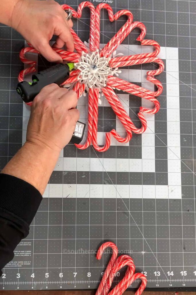 gluing the snowflake ornament to the center of the candy cane wreath