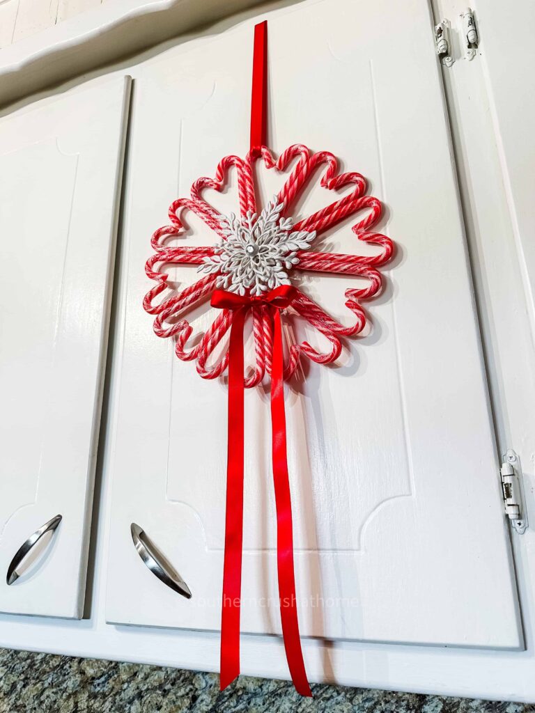 candy cane wreath hanging on a kitchen cabinet