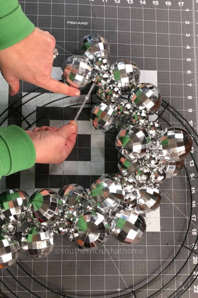 attaching disco ball garland to wreath frame using zip ties