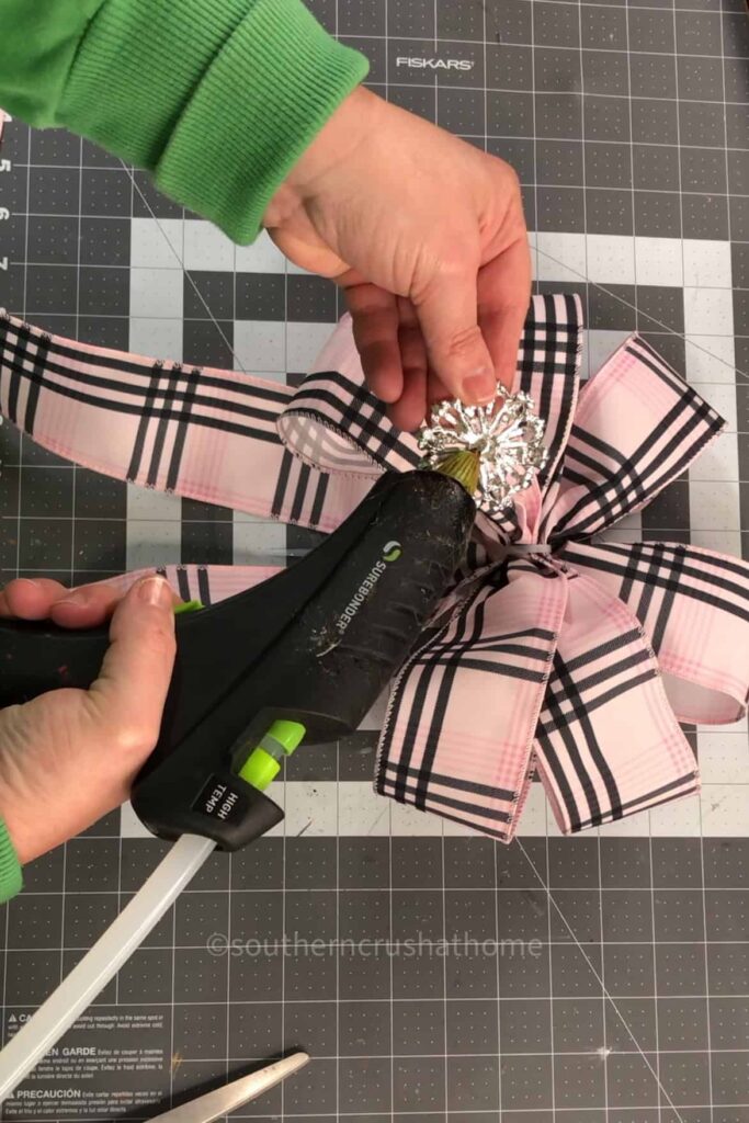 attaching a rhinestone embellishment to the center of the bow