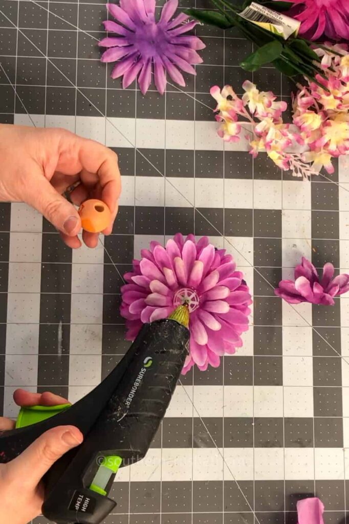 hot gluing the wood bead to the center of the flower fairy