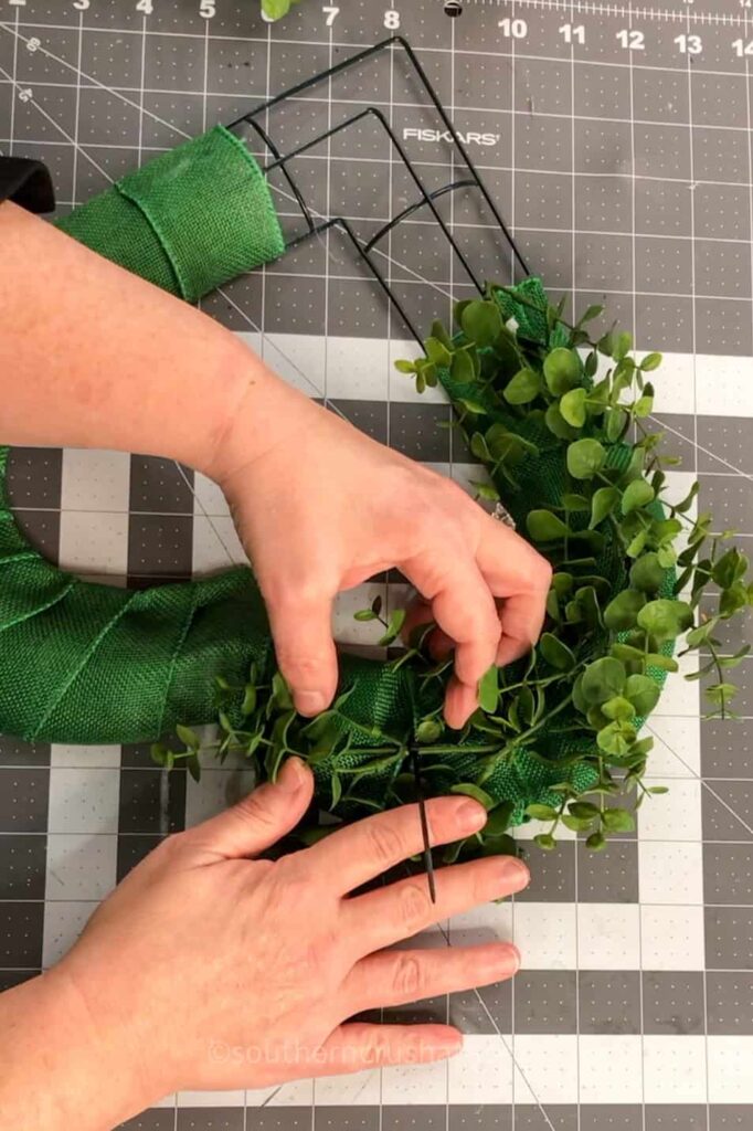 tucking boxwood sprigs into heart wreath