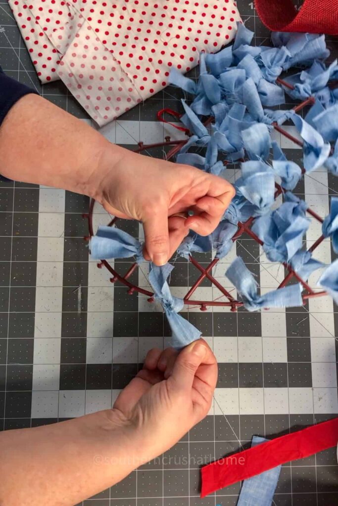 tying knots of fabric scraps on dollar tree wreath frame