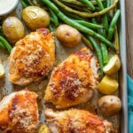 Parmesan crusted chicken thighs with green beans and baby potatoes on a sheet pan.